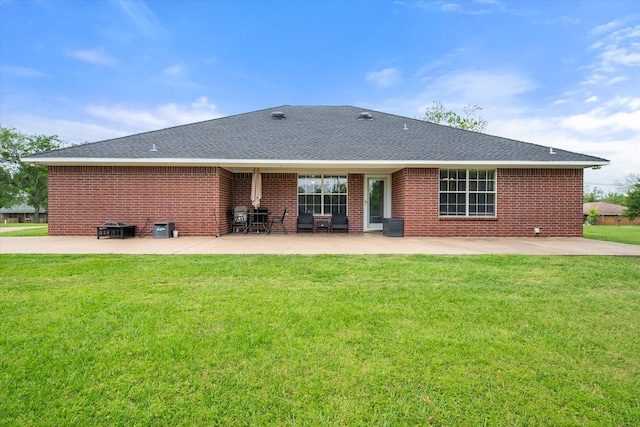 rear view of house with a patio area, a lawn, brick siding, and roof with shingles