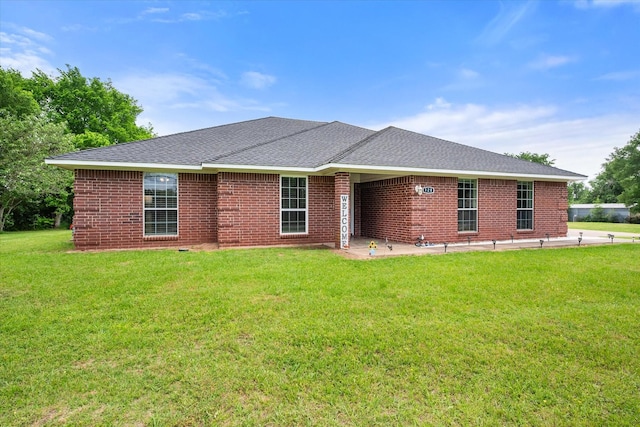 view of front of house featuring brick siding, a shingled roof, and a front yard