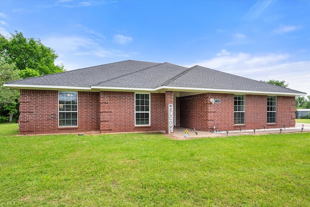 back of house with brick siding, a yard, a patio, and a shingled roof