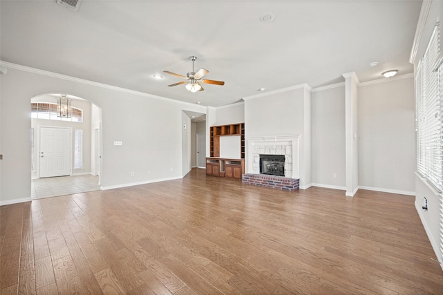 1919 Water Fall Way, Wylie, TX 75098 - unfurnished living room featuring a ceiling fan, a fireplace, arched walkways, wood finished floors, and baseboards