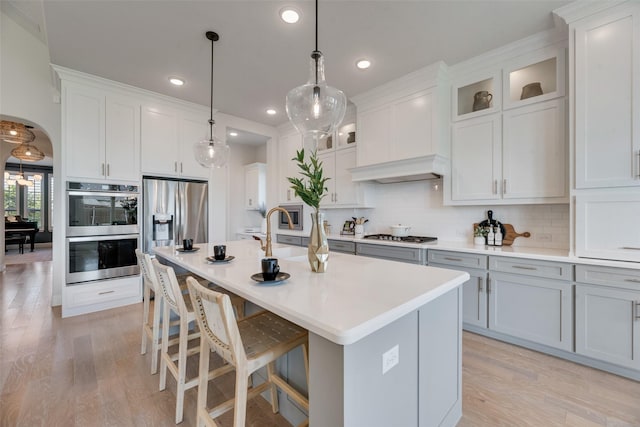 3101 Twin Eagles Dr, Celina, TX 75009 - kitchen with appliances with stainless steel finishes, an island with sink, a kitchen bar, light wood-style floors, and backsplash