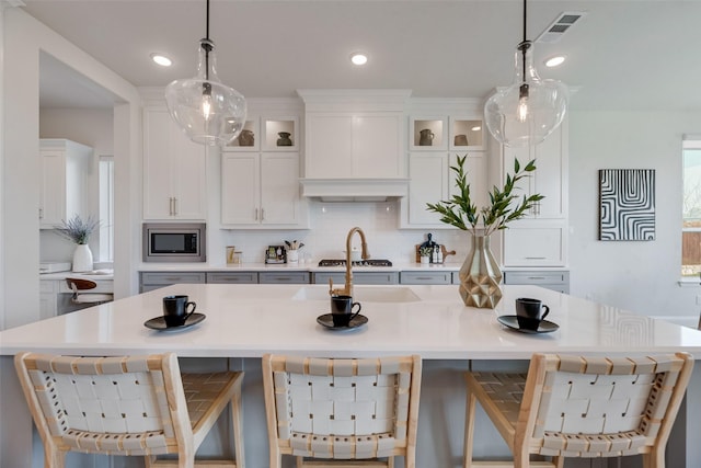 3101 Twin Eagles Dr, Celina, TX 75009 - kitchen featuring an island with sink, white cabinetry, light countertops, visible vents, and appliances with stainless steel finishes