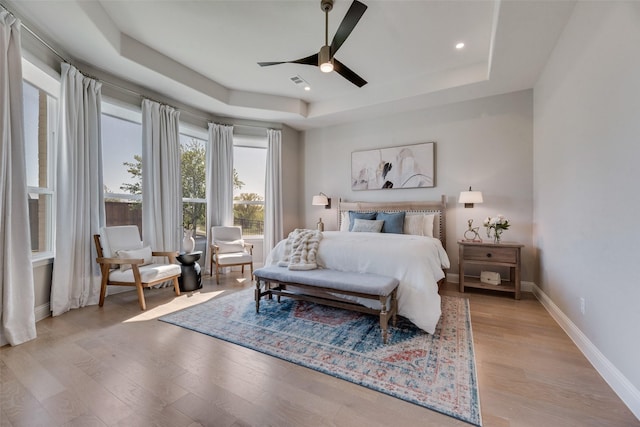 3101 Twin Eagles Dr, Celina, TX 75009 - bedroom with light wood-type flooring, baseboards, visible vents, a tray ceiling, and ceiling fan