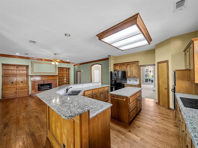 1213 Hills Creek Dr, Mckinney, TX 75072 - kitchen featuring black appliances, a spacious island, a ceiling fan, a fireplace, and a sink