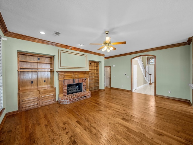 1213 Hills Creek Dr, Mckinney, TX 75072 - unfurnished living room featuring arched walkways, ornamental molding, ceiling fan, a fireplace, and wood finished floors