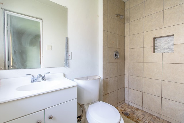 full bath with vanity, a tile shower, and toilet