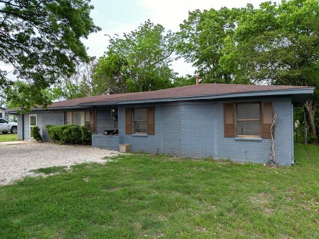 ranch-style home featuring driveway, a front yard, and brick siding