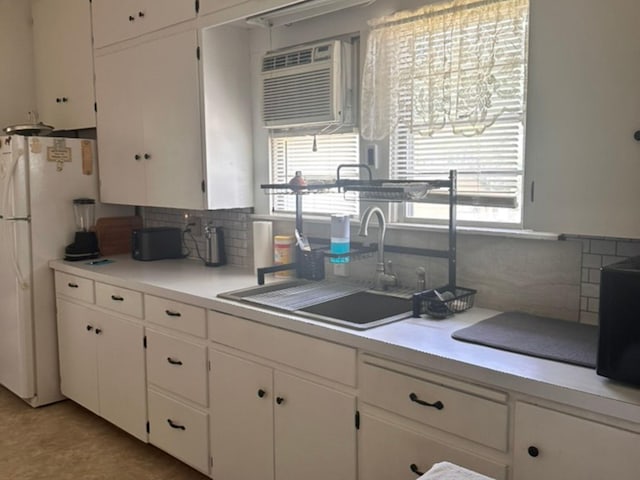 kitchen with a healthy amount of sunlight, freestanding refrigerator, a sink, and backsplash