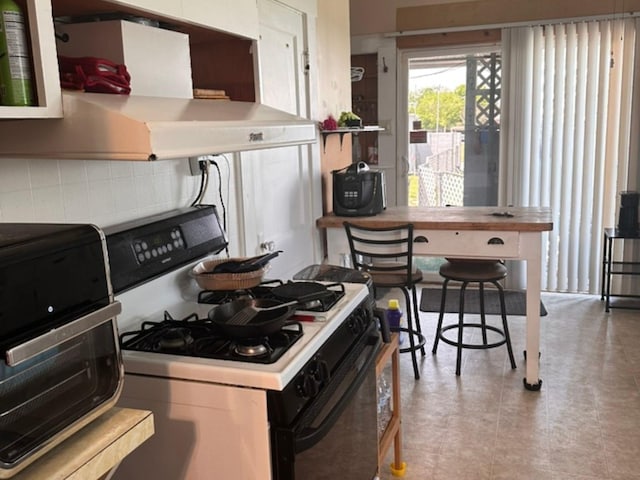 kitchen featuring white cabinets, gas range, ventilation hood, light countertops, and backsplash