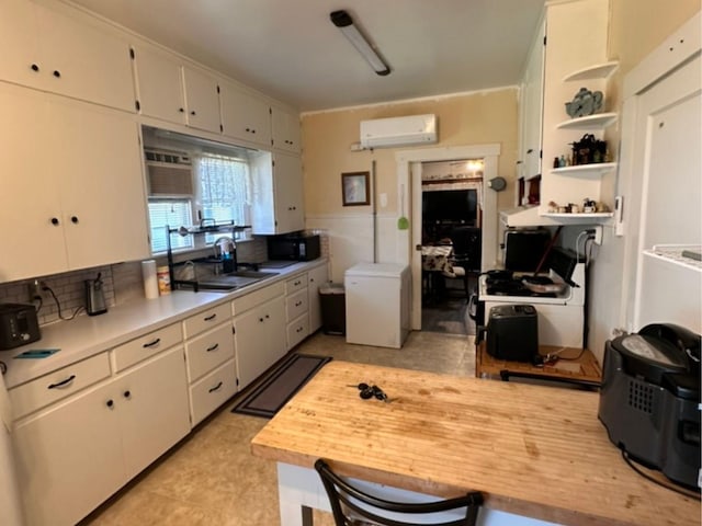 kitchen featuring refrigerator, a wall mounted air conditioner, light countertops, open shelves, and a sink