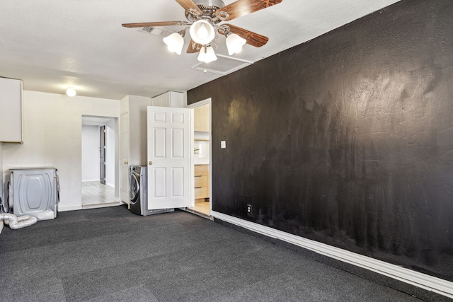 spare room featuring dark carpet, baseboards, a ceiling fan, and washer / dryer
