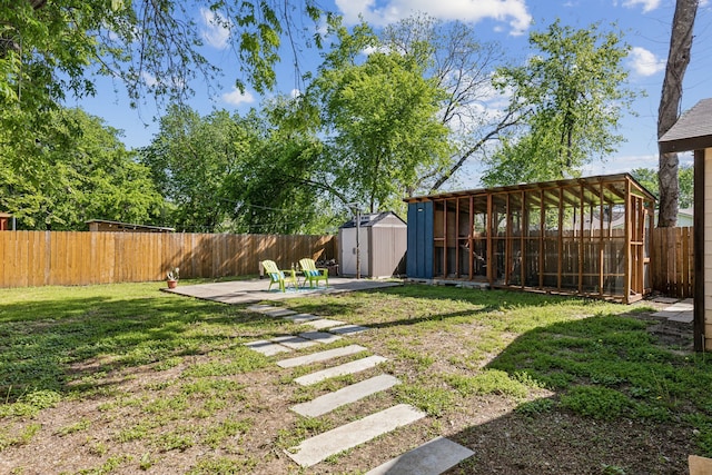 view of yard featuring a shed, a patio, a fenced backyard, and an outbuilding