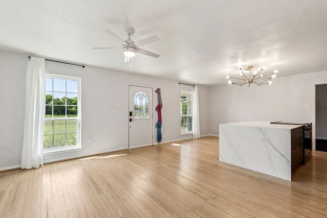 foyer featuring light wood-style flooring, baseboards, and ceiling fan with notable chandelier