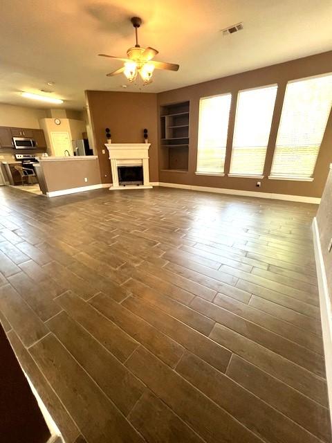 518 Lonestar Park Ln, Ponder, TX 76259 - unfurnished living room featuring ceiling fan, built in features, a fireplace, and dark wood finished floors