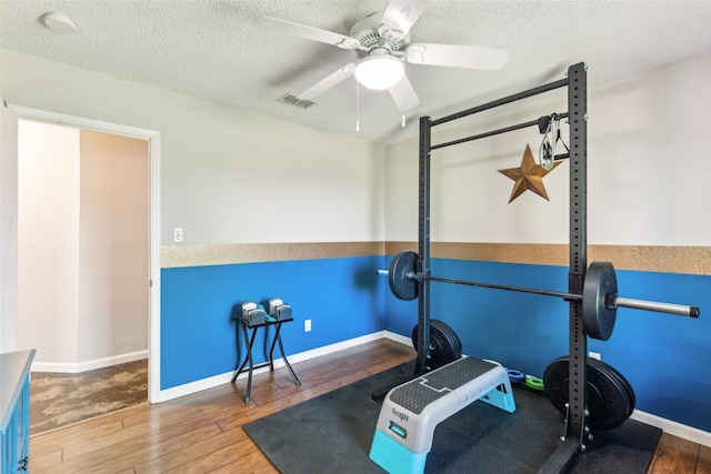 workout area with visible vents, a textured ceiling, ceiling fan, and wood-type flooring