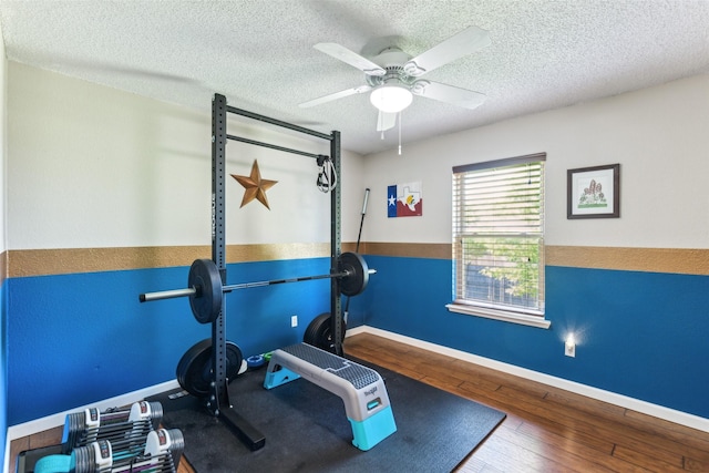 workout room with hardwood / wood-style floors, a ceiling fan, baseboards, and a textured ceiling