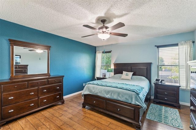 bedroom featuring baseboards, a ceiling fan, wood finished floors, and a textured ceiling