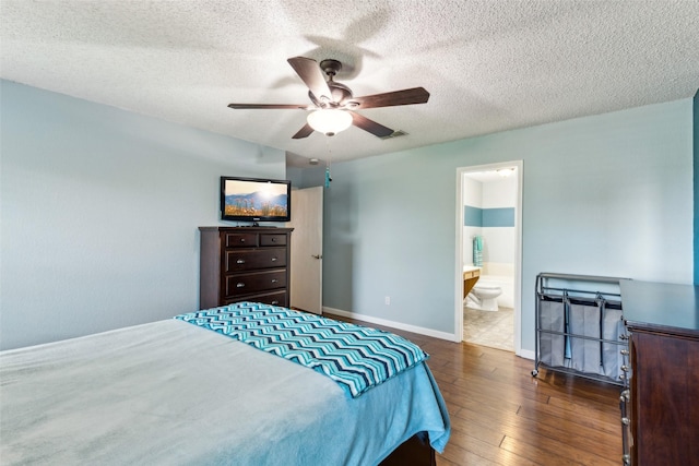 bedroom featuring a ceiling fan, a textured ceiling, ensuite bathroom, dark wood finished floors, and baseboards