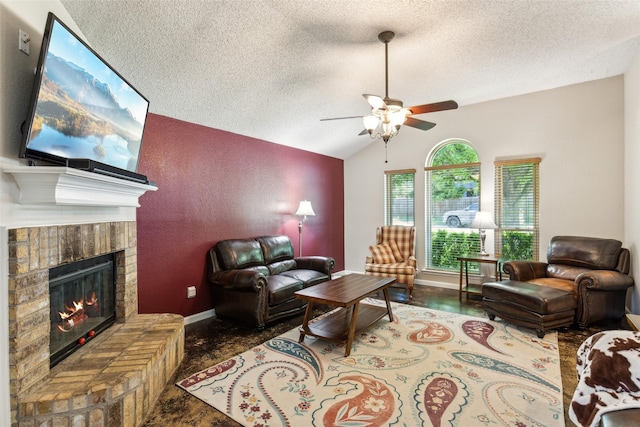 living area with vaulted ceiling, a ceiling fan, a textured ceiling, baseboards, and a brick fireplace