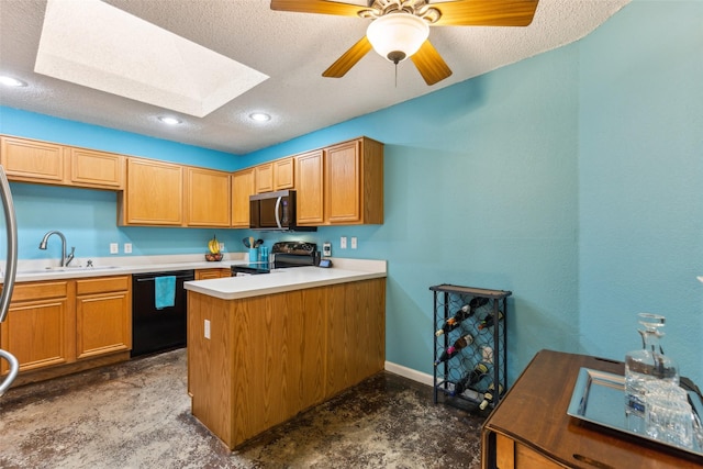 kitchen with a sink, a skylight, a peninsula, a textured ceiling, and appliances with stainless steel finishes
