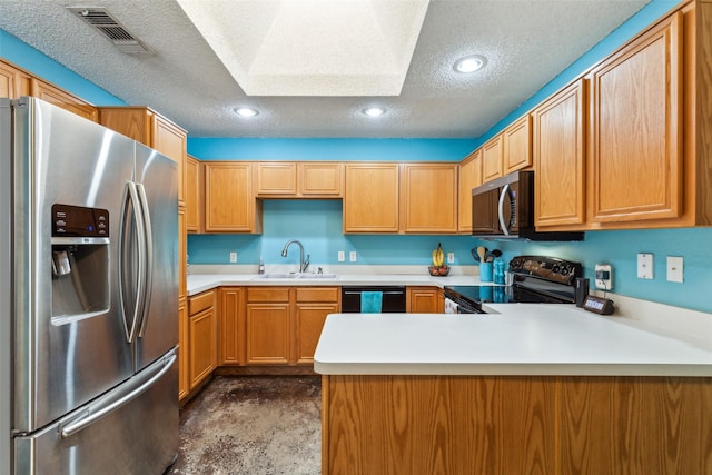kitchen featuring a peninsula, a sink, a textured ceiling, light countertops, and appliances with stainless steel finishes
