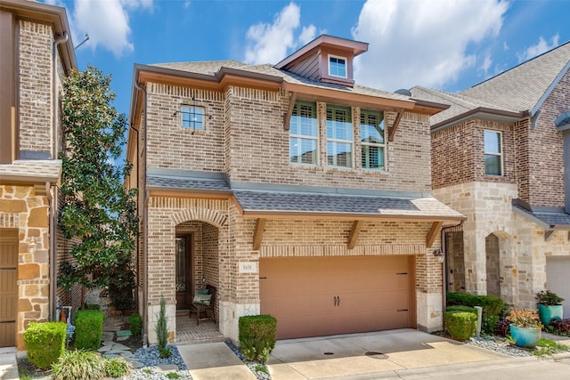multi unit property with roof with shingles, a garage, concrete driveway, and brick siding