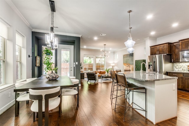kitchen with light stone counters, a center island with sink, a breakfast bar area, stainless steel appliances, and a sink
