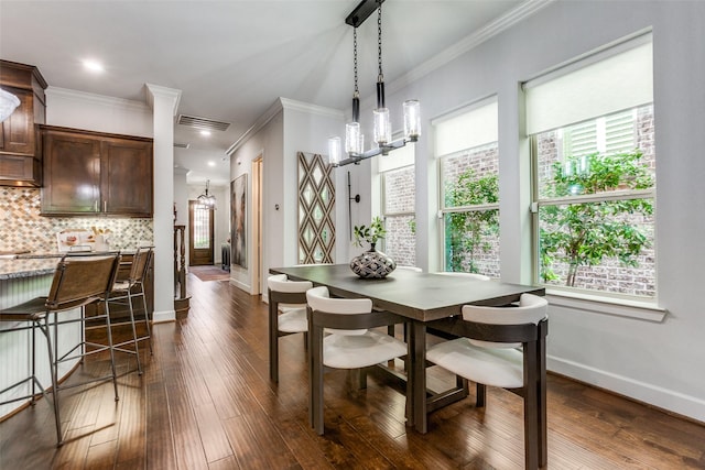 dining space featuring dark wood-style flooring, baseboards, ornamental molding, and visible vents