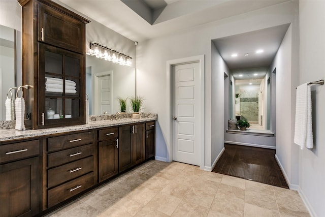 bathroom with tile patterned flooring, baseboards, vanity, and walk in shower