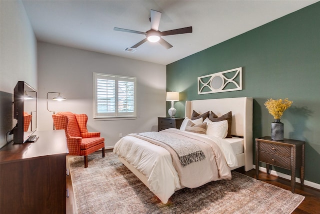bedroom featuring visible vents, baseboards, ceiling fan, and wood finished floors
