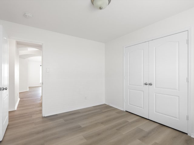 6813 Falconer Way, Fort Worth, TX 76179 - unfurnished bedroom featuring arched walkways, light wood-style flooring, baseboards, and a closet