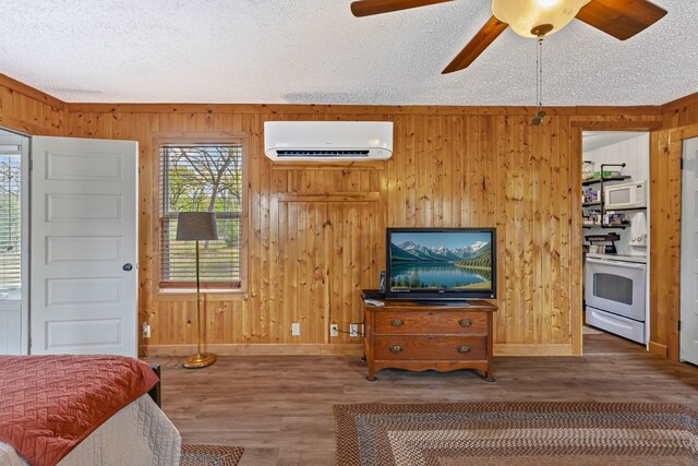 bedroom with wood finished floors, wooden walls, baseboards, and an AC wall unit