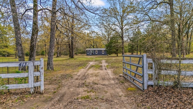 exterior space featuring dirt driveway, fence, and a gate
