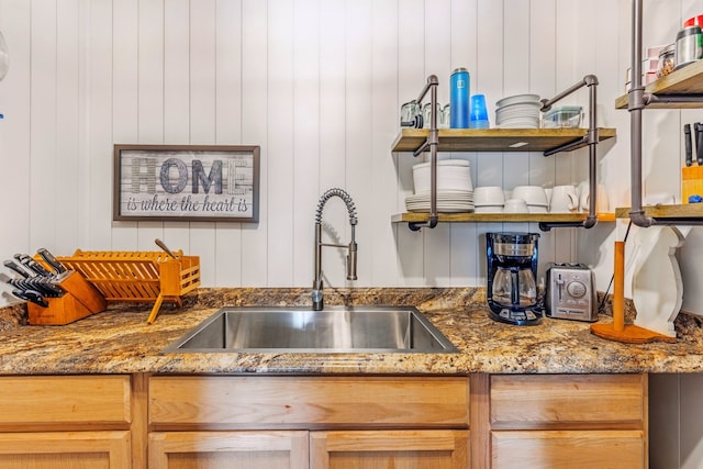 interior space featuring stone countertops, wooden walls, a sink, and open shelves