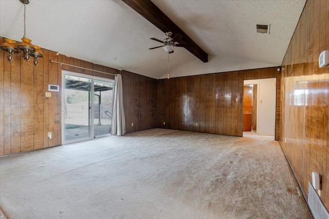 empty room featuring a ceiling fan, a textured ceiling, wooden walls, vaulted ceiling with beams, and light colored carpet