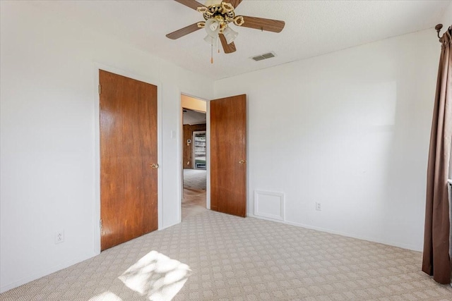 unfurnished bedroom featuring visible vents, a ceiling fan, and carpet flooring