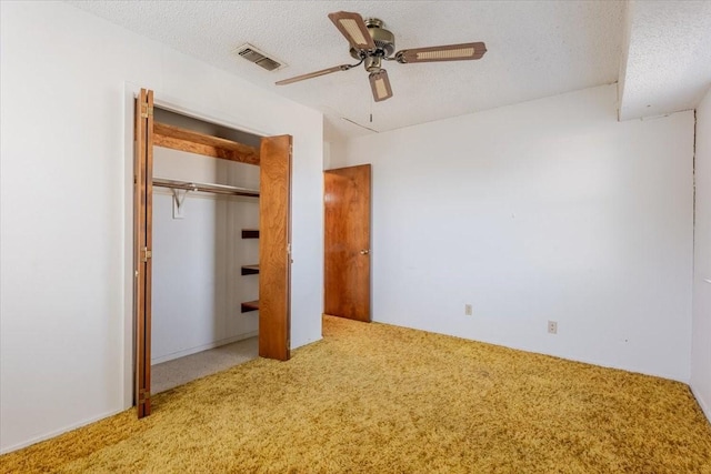 unfurnished bedroom with ceiling fan, a textured ceiling, a closet, visible vents, and carpet flooring