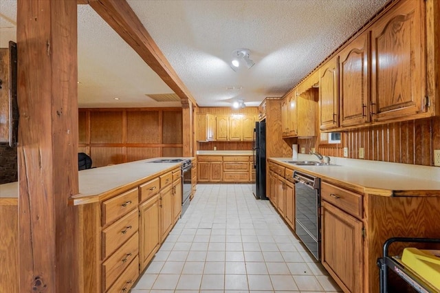 kitchen with light tile patterned floors, black appliances, wood walls, light countertops, and a sink