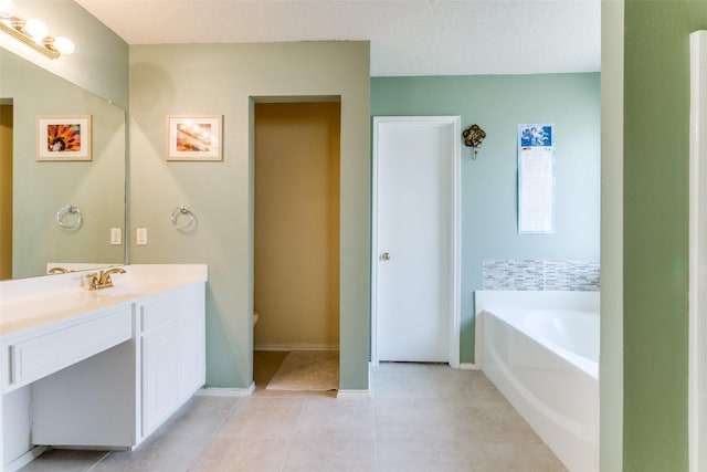 full bathroom with a bath, tile patterned floors, baseboards, and vanity