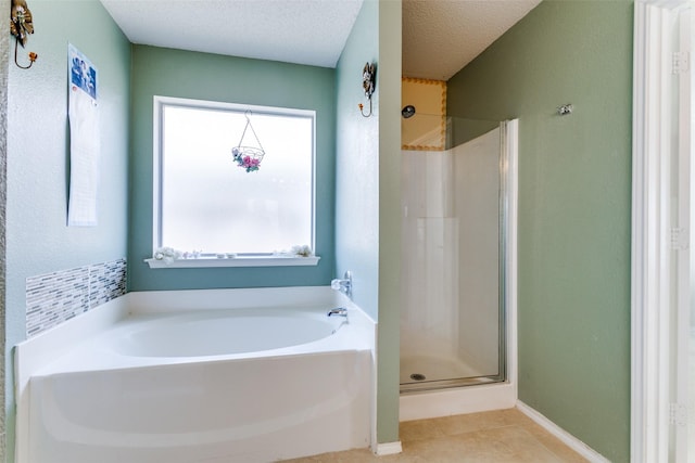 bathroom with tile patterned flooring, a bath, a textured ceiling, and a stall shower
