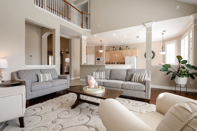 living room with baseboards, decorative columns, a high ceiling, and dark wood finished floors
