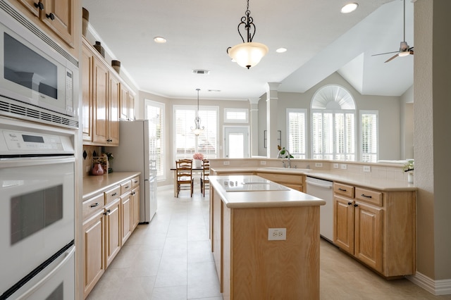 kitchen with light brown cabinets, a sink, white appliances, light countertops, and a kitchen island