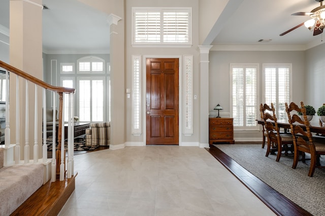 foyer entrance featuring stairway, a wealth of natural light, a ceiling fan, and ornamental molding