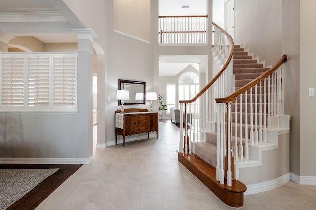 foyer featuring baseboards, a high ceiling, stairs, and visible vents