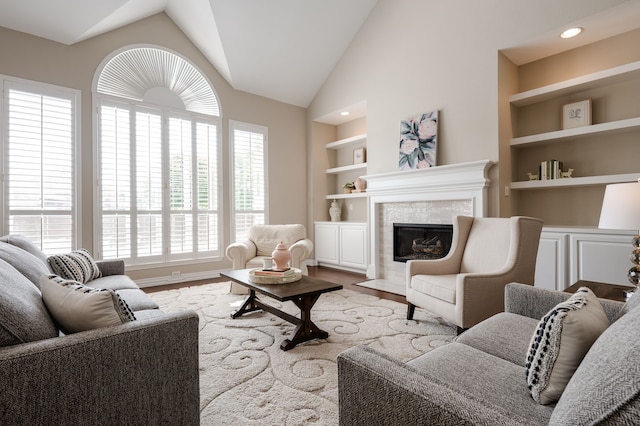 living room featuring lofted ceiling, wood finished floors, a fireplace, and built in shelves
