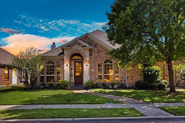 9409 Stonewood Dr, Mckinney, TX 75072 - view of front of house featuring a yard, a chimney, brick siding, roof with shingles, and stone siding