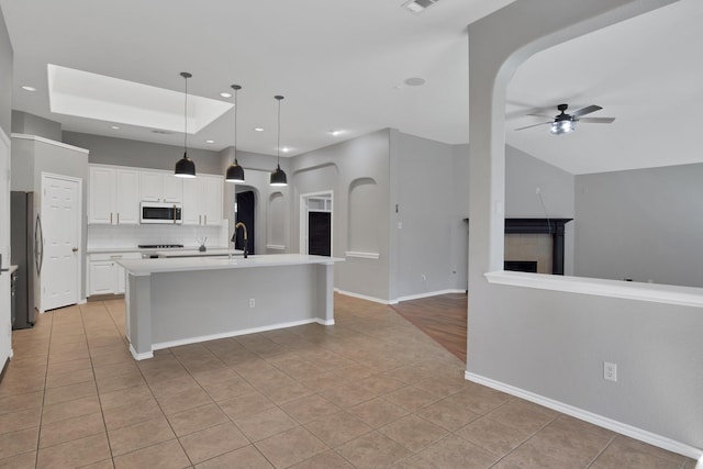 9409 Stonewood Dr, Mckinney, TX 75072 - kitchen with white microwave, freestanding refrigerator, arched walkways, light tile patterned floors, and a ceiling fan