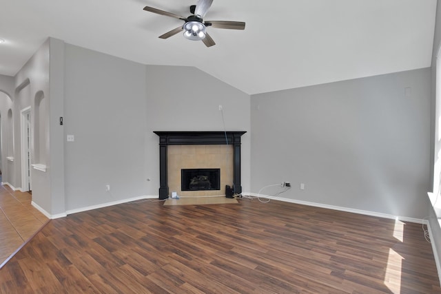 9409 Stonewood Dr, Mckinney, TX 75072 - unfurnished living room with arched walkways, a ceiling fan, wood finished floors, a tile fireplace, and lofted ceiling