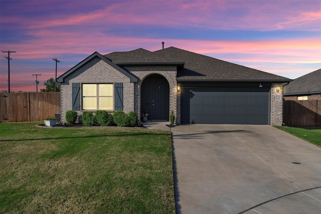 ranch-style home with concrete driveway, an attached garage, brick siding, a yard, and fence