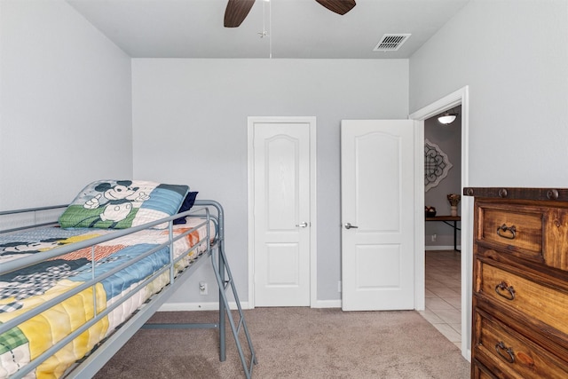 carpeted bedroom with visible vents, baseboards, and a ceiling fan